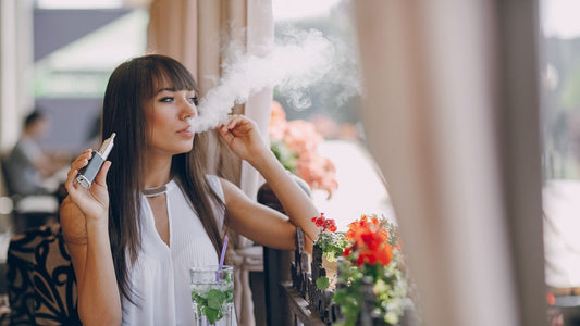 Lady vaping with a YOOZ device at a cafe